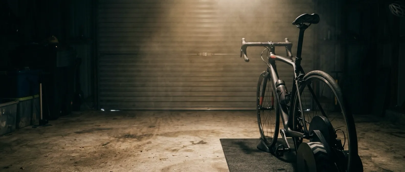 The garage from behind the bike: the roller door shut, the saddle empty, the lamp still on.